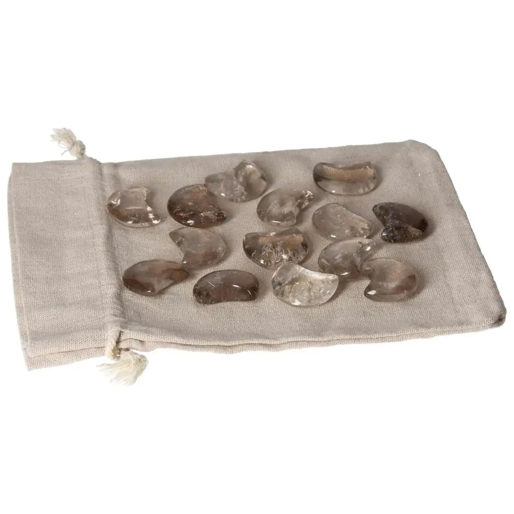 Small moon-shaped smoky quartz stones on a fabric pouch, ideal for decision making and emotional balance.