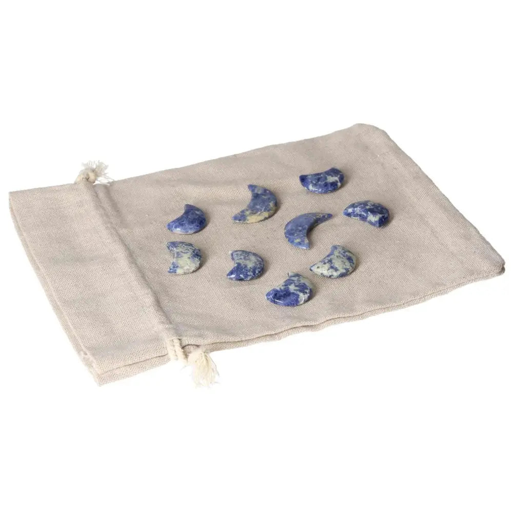 Collection of small Sodalite crescent moons on a beige pouch, symbolizing intuition and emotional balance with deep indigo and white tones.