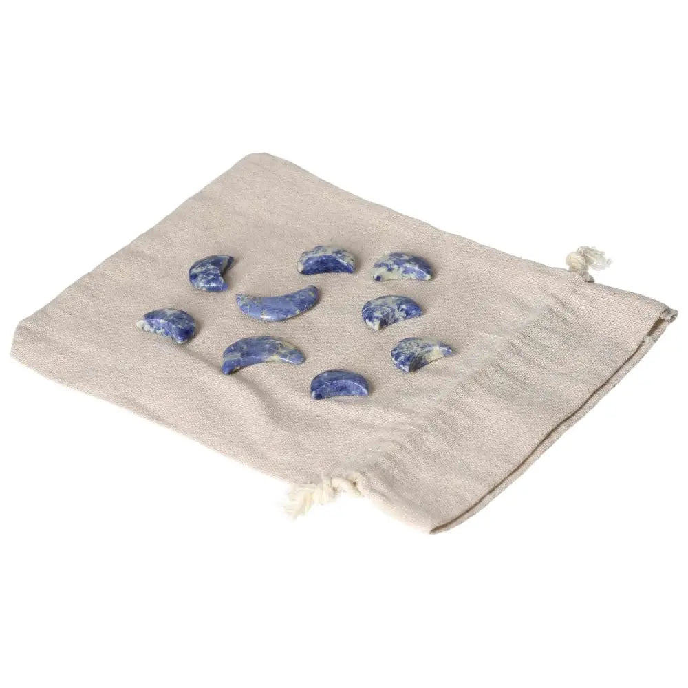 Small Sodalite crescent moons on a beige fabric bag, symbolizing intuition, emotional balance, and mental clarity with indigo and white tones.
