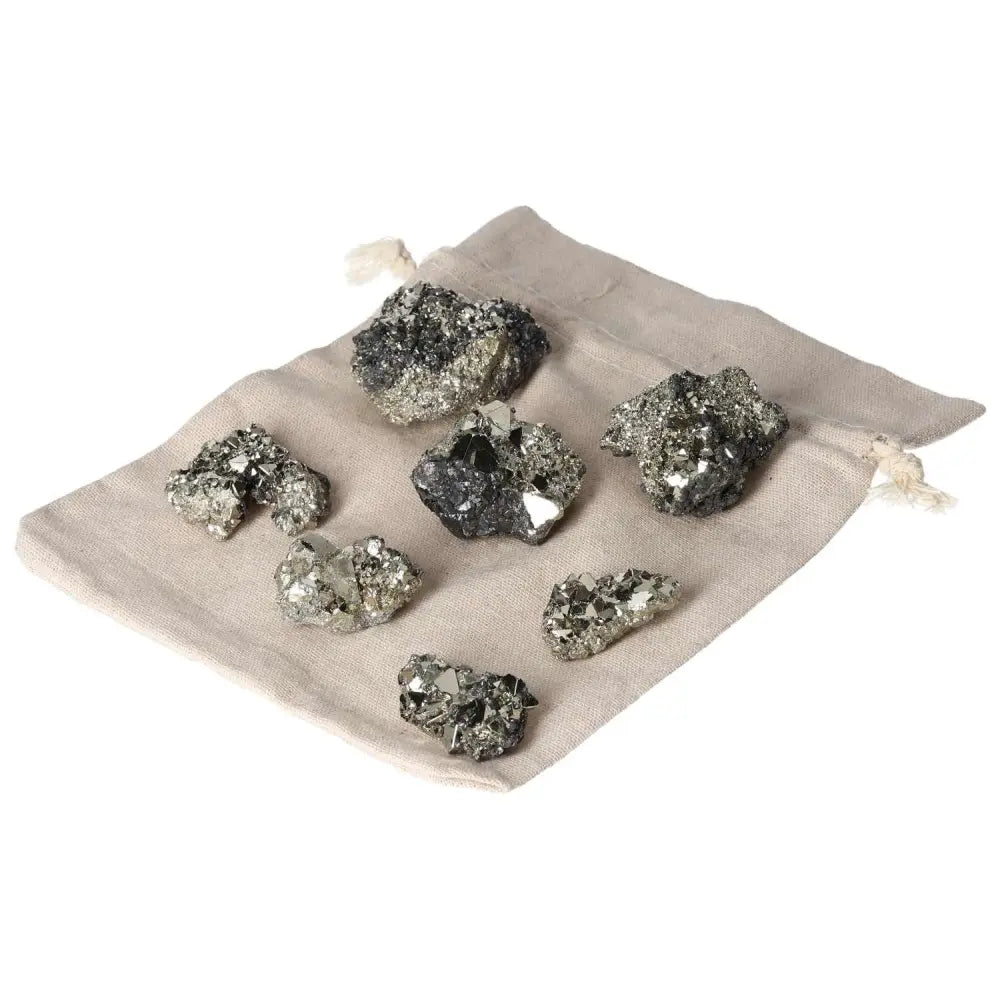 Pyrite clusters with metallic luster on a beige cloth bag, showcasing geometric formations and natural brilliance.