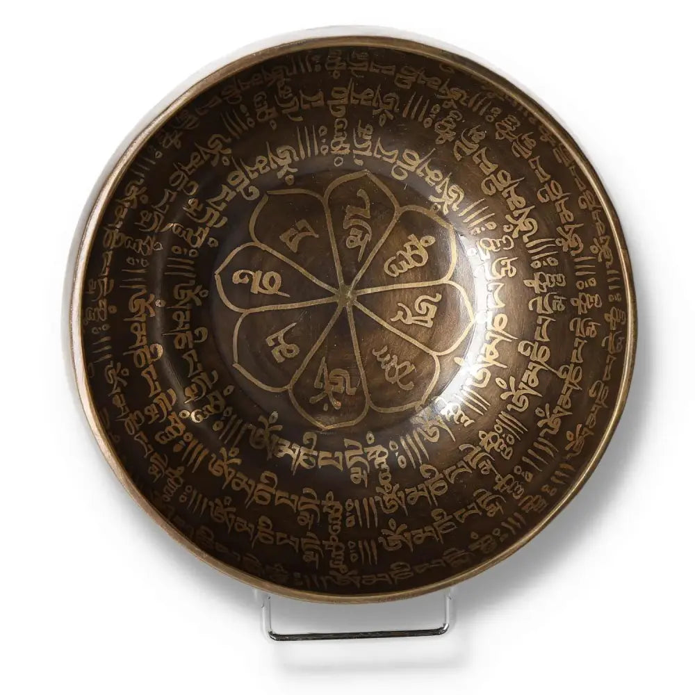 Tibetan healing bowl with intricate mantra engravings, 16 cm in diameter, viewed from above on a stand.