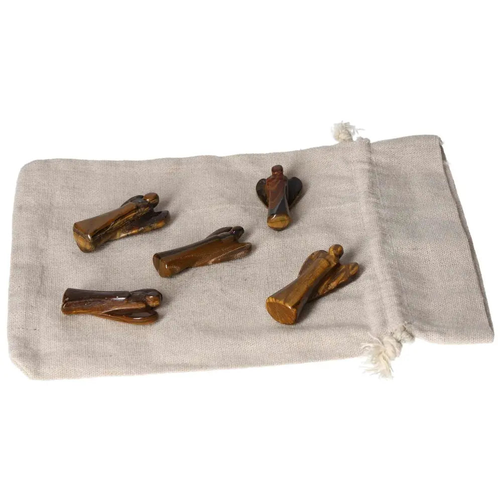 Small Tiger's Eye angel figurines on fabric, symbolizing protection, strength, and divine guidance with golden-brown shimmer.