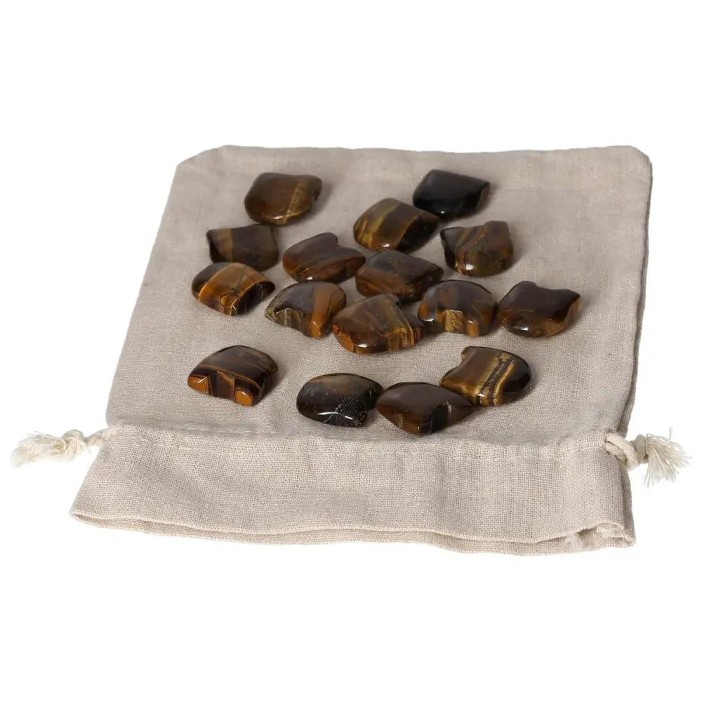Collection of Tiger's Eye small stones on a beige cloth bag, known for enhancing mental clarity and supporting joy and stability.