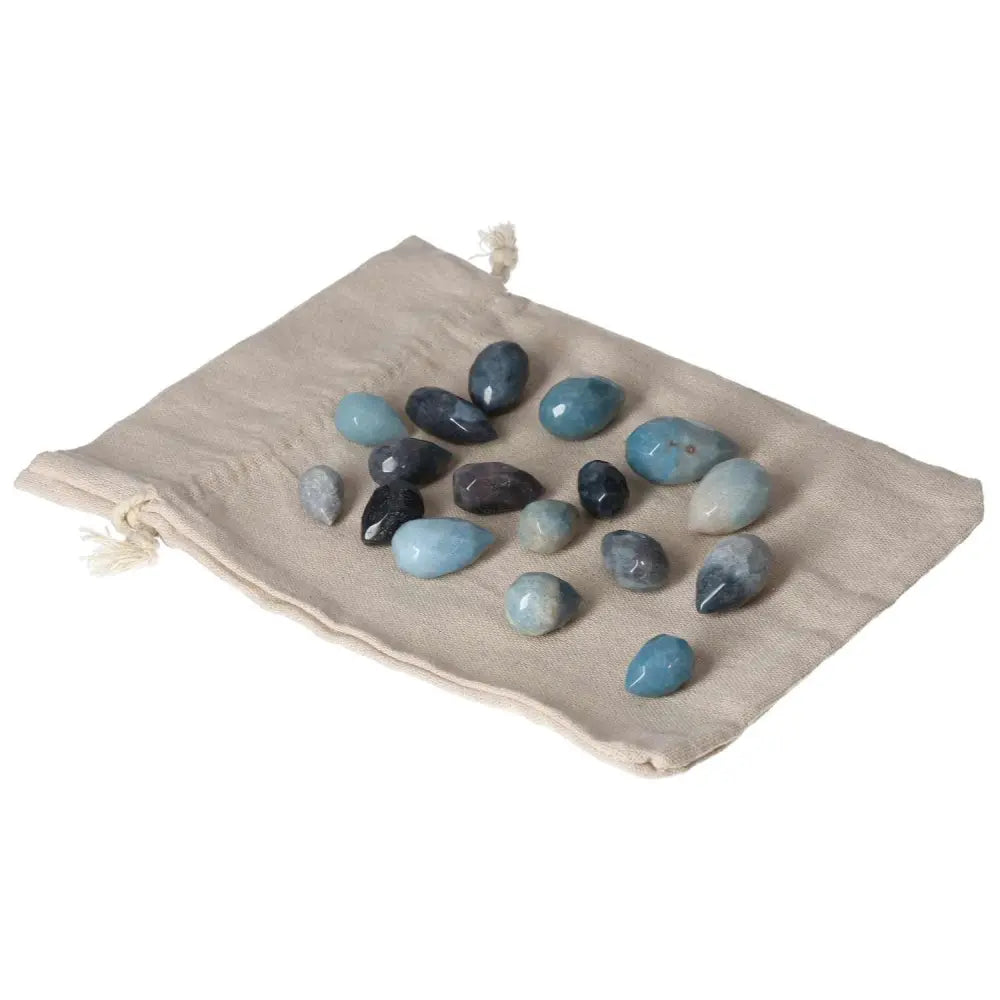 Assorted Trolleite stones in blue hues on beige cloth, symbolizing spiritual intuition and chakra activation.