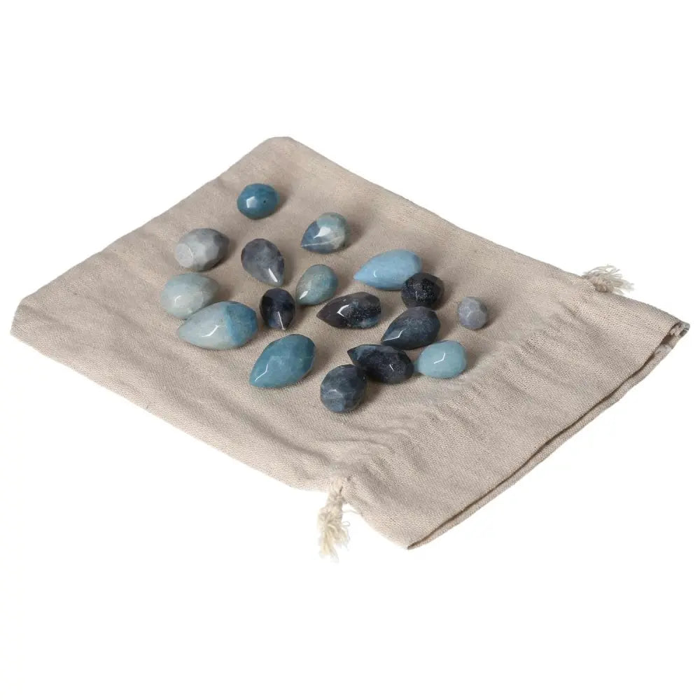 Collection of small blue to violet Trolleite stones symbolizing intuition and spiritual awareness, on a beige fabric pouch.