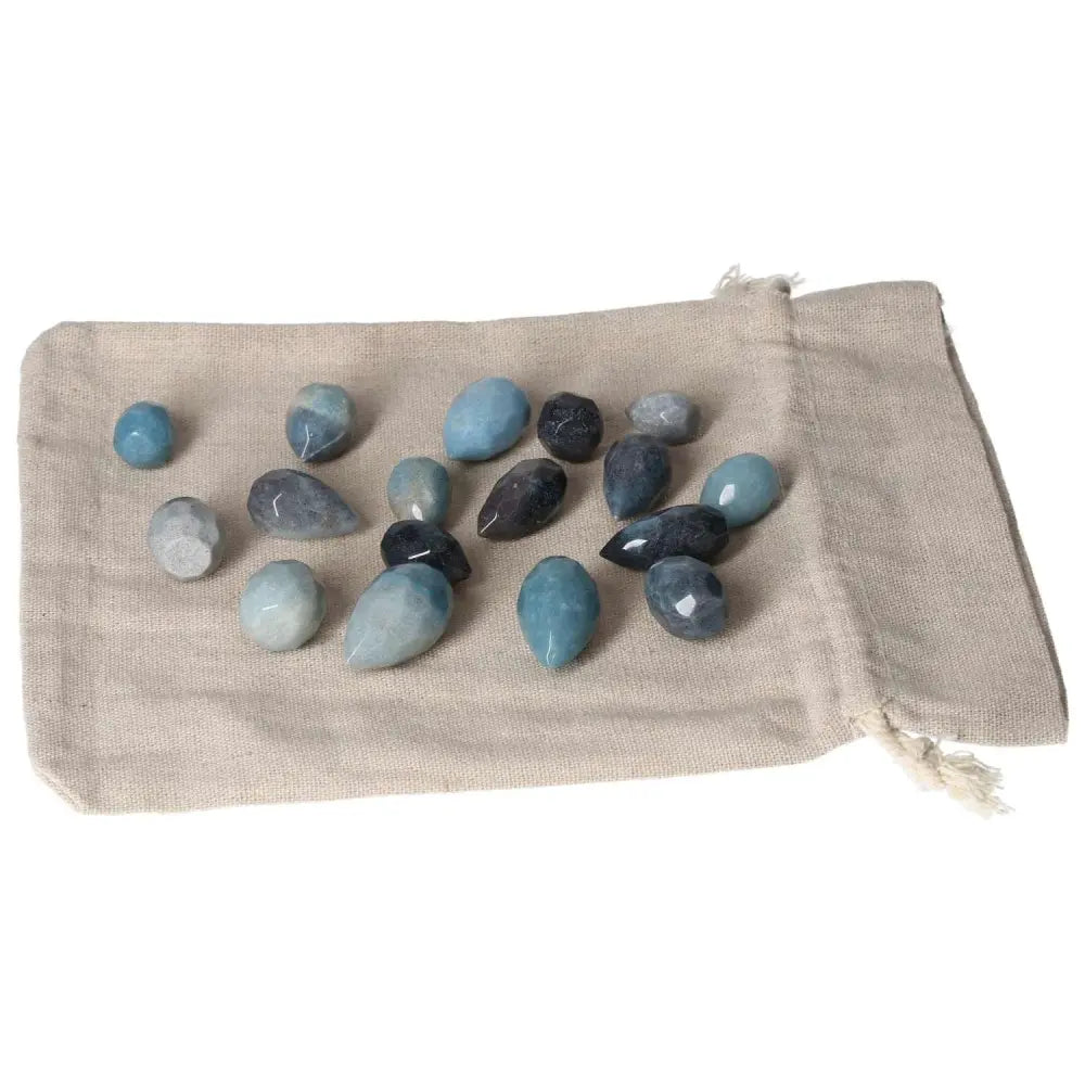 Assorted trolleite tear-shaped stones in blue and violet hues on a beige cloth bag, symbolizing intuition and spiritual awareness.