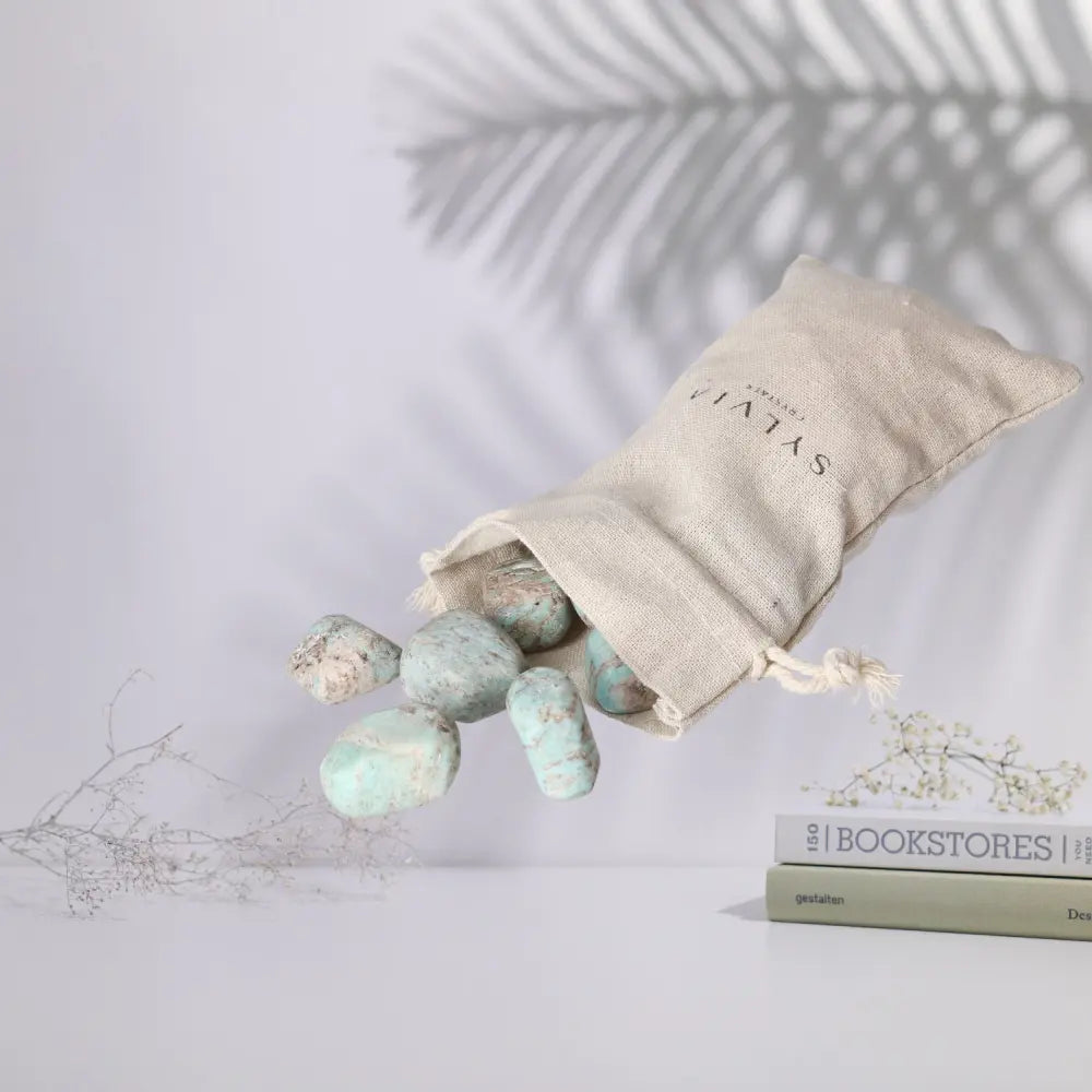 Tumbled Amazonite gemstones spilling from a canvas bag, showcasing calming turquoise hues, ideal for emotional balance and clarity.
