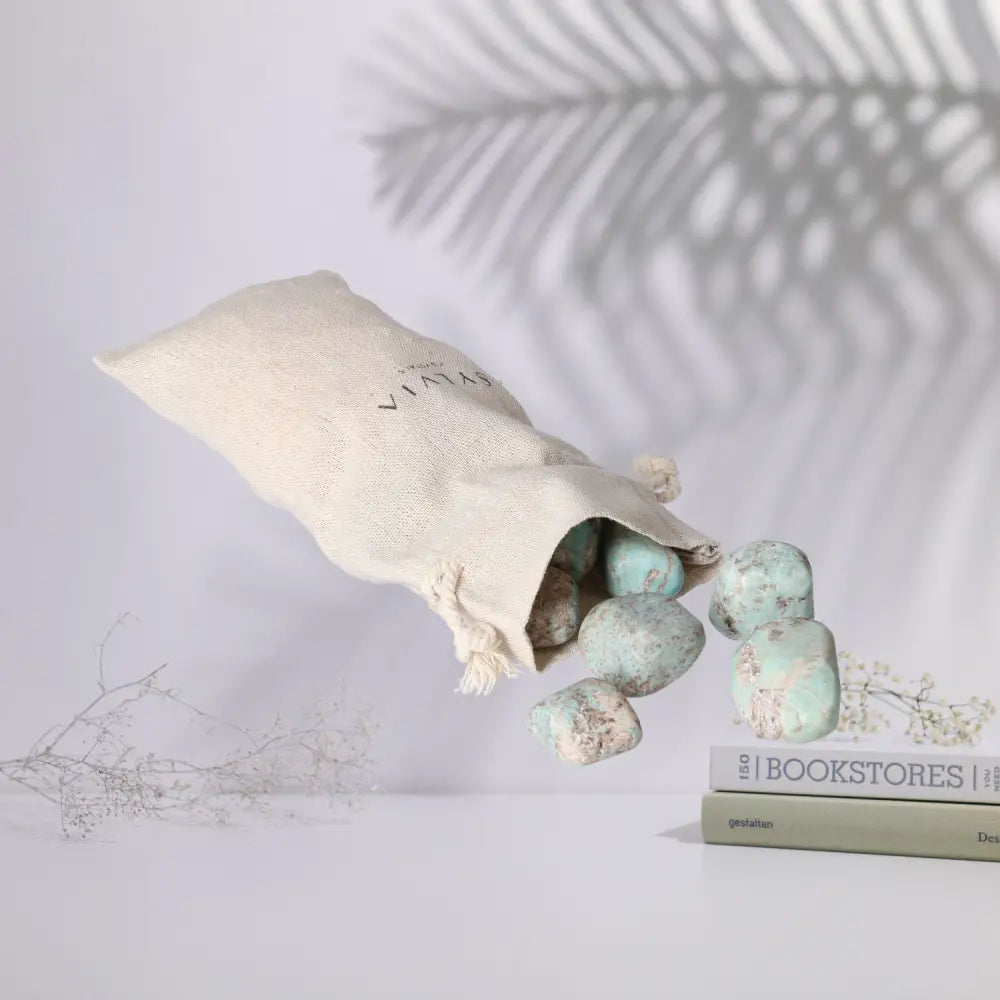 Tumbled Amazonite stones spilling from a linen pouch, showcasing natural turquoise and green patterns, promoting emotional balance.