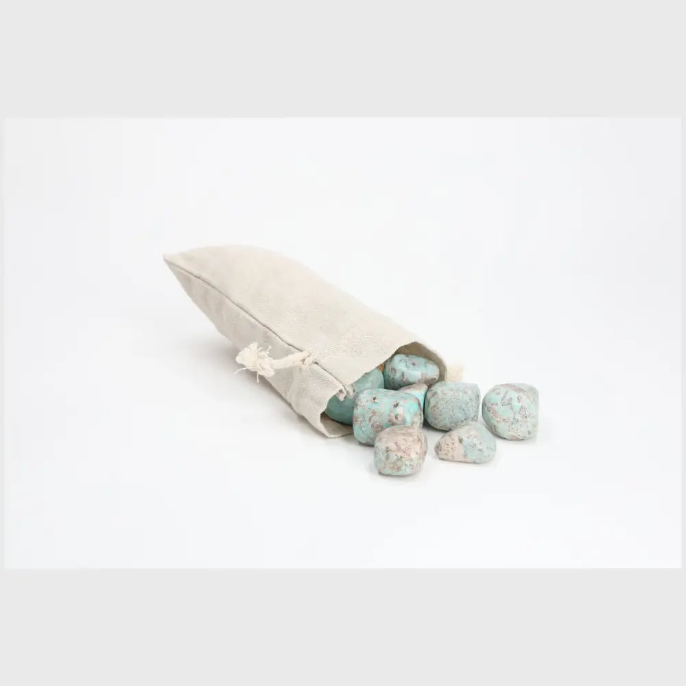 Tumbled Amazonite stones spilling from a beige pouch, showcasing calming shades of turquoise and green, ideal for promoting balance.