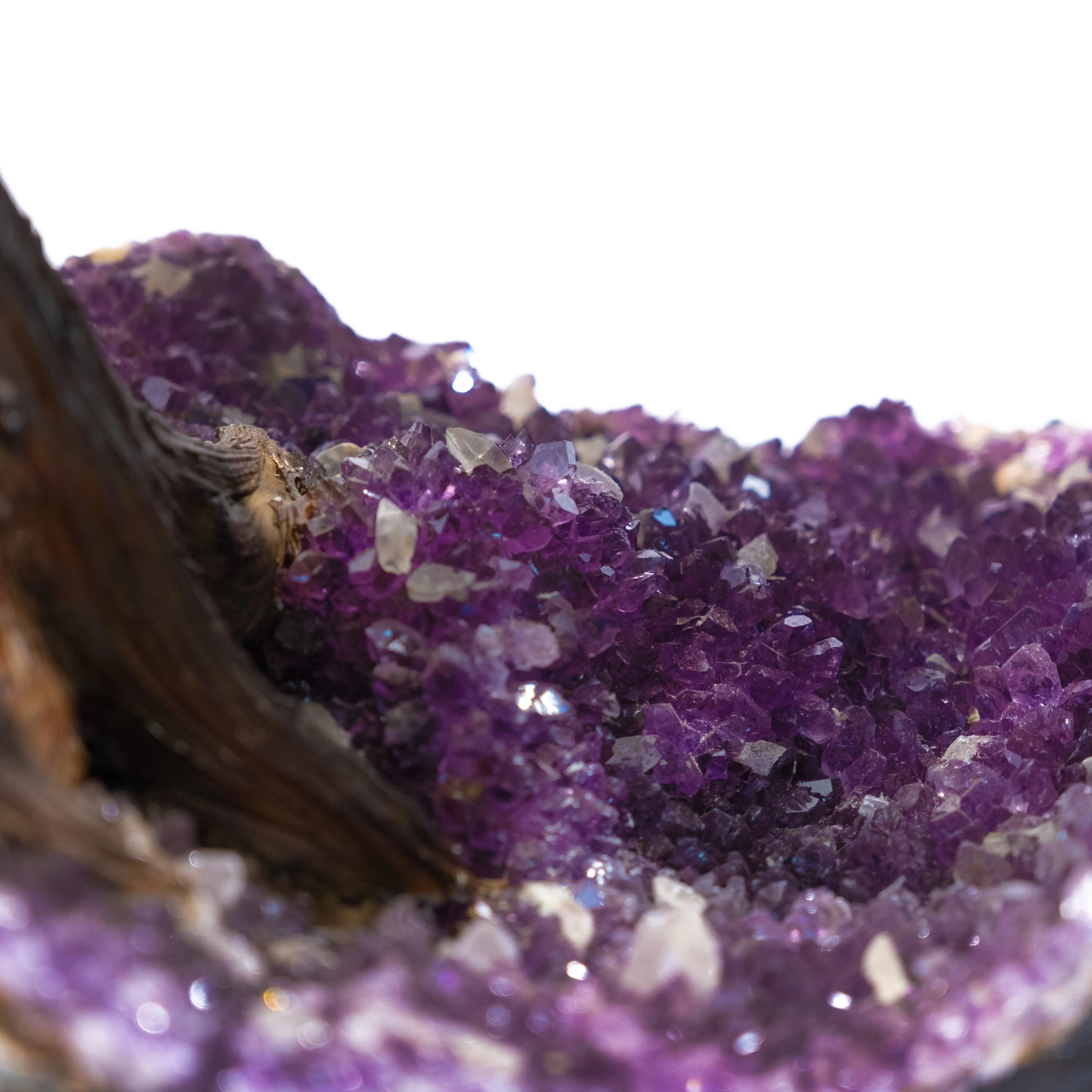 Close-up of a sparkling purple gemstone cluster on a crystal formation with a wooden accent, showcasing vibrant amethyst hues.