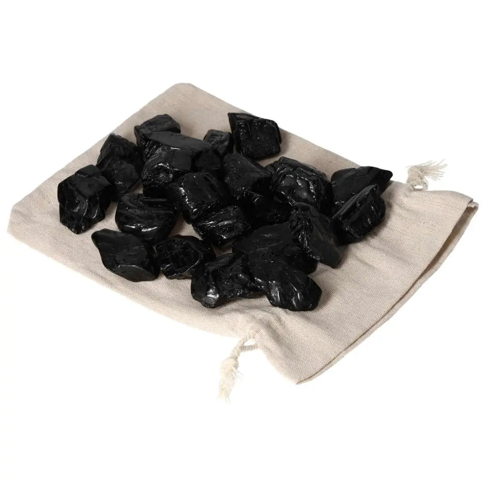 Tumbled Black Tourmaline L crystals on a beige pouch, known for cleansing energy and promoting mental clarity.