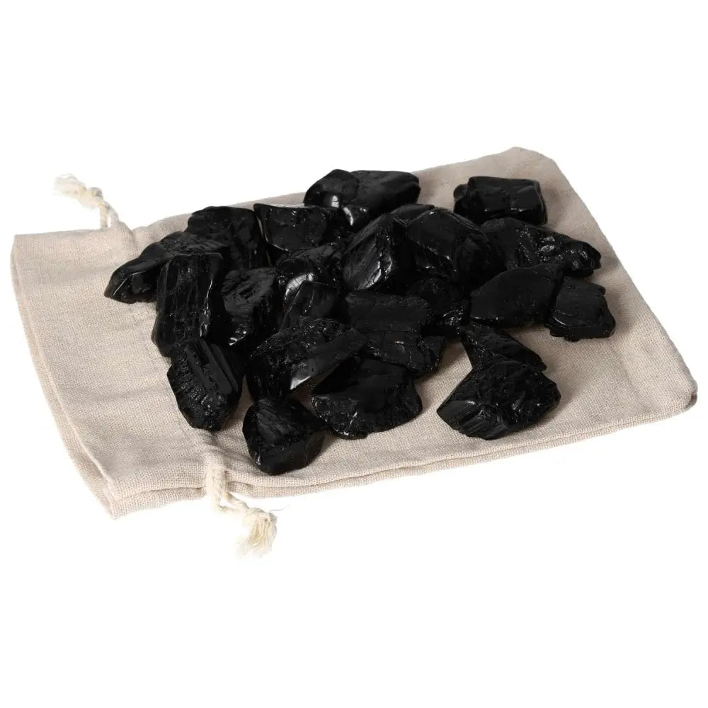 Tumbled Black Tourmaline L crystal pieces on a beige cloth, known for cleansing negative energy and promoting mental clarity.