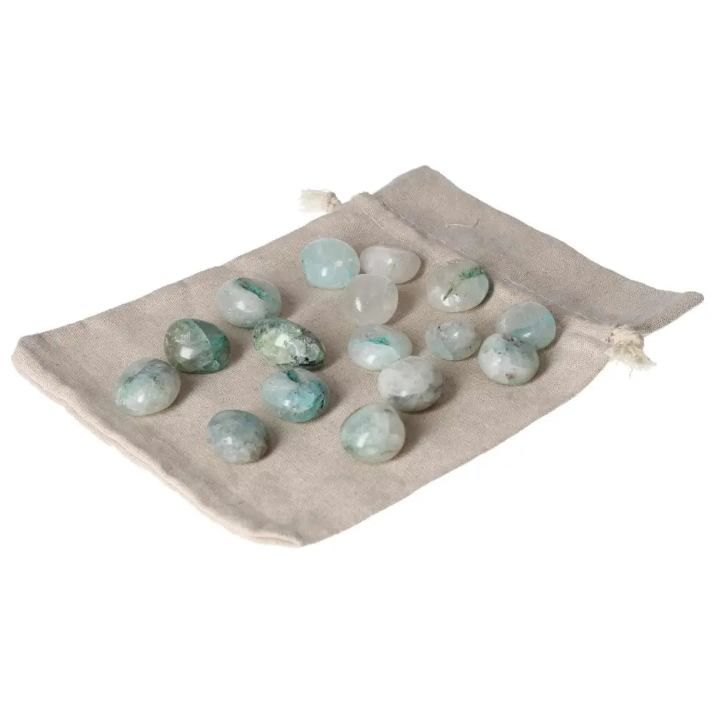 Tumbled Chrysocolla stones on a beige pouch, known for enhancing speech clarity and feminine energy benefits.