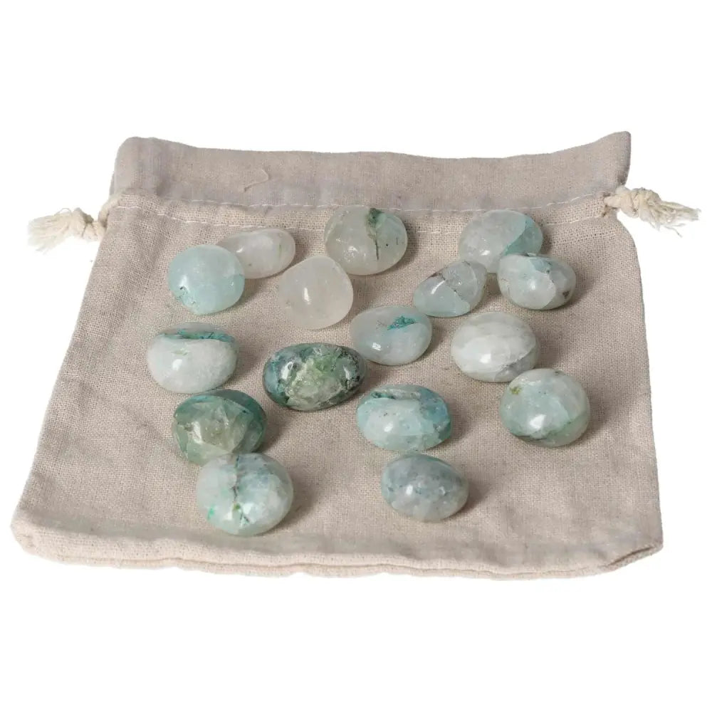 Tumbled Chrysocolla stones on a beige cloth bag, showcasing their calming green and blue hues, ideal for enhancing communication.