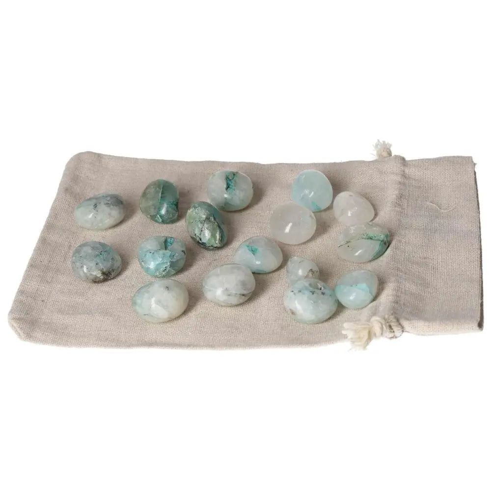 Collection of tumbled chrysocolla stones on a beige pouch, emphasizing feminine energy and communication enhancement.