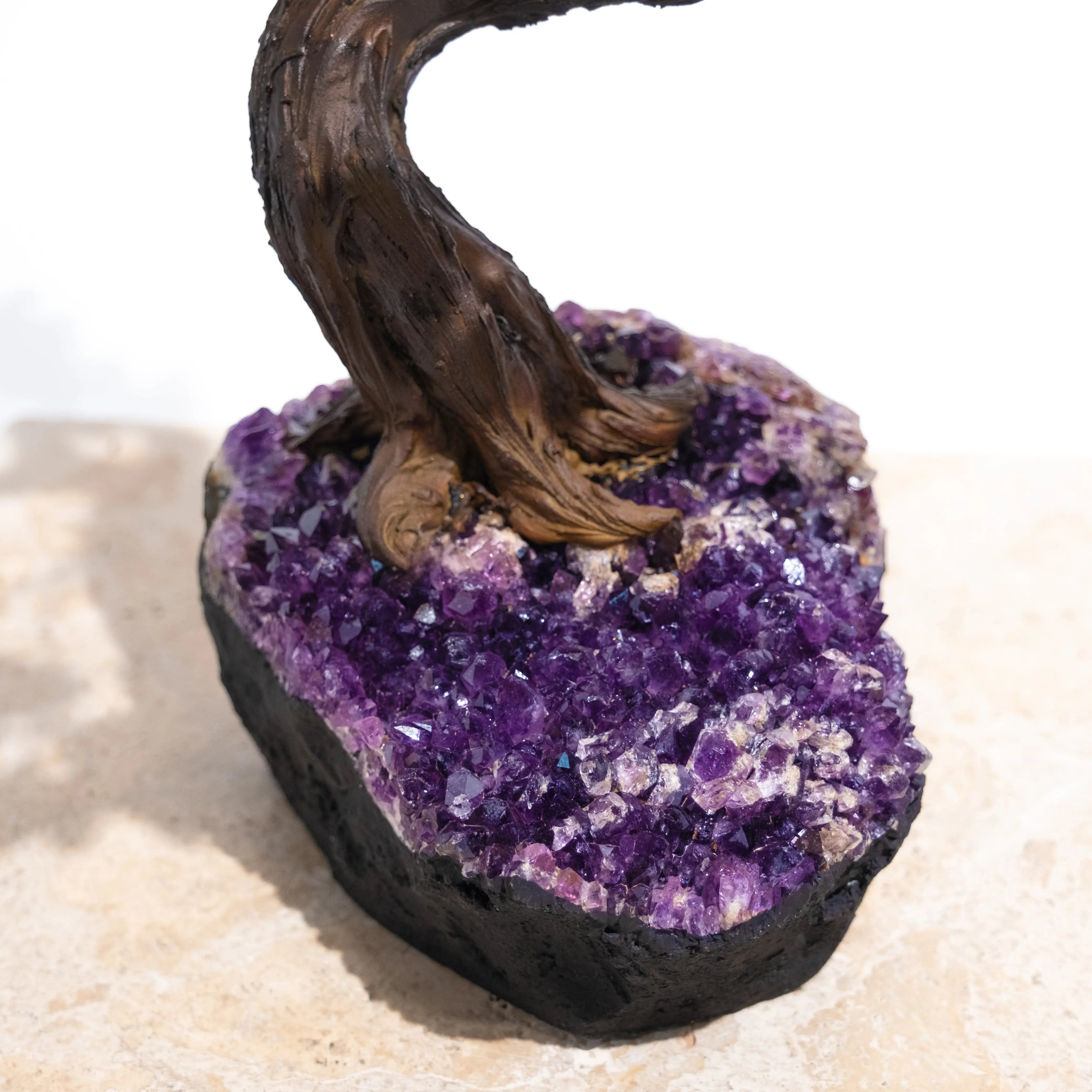 Purple gemstone base with twisting tree trunk on an artistic sculpture, symbolizing tranquility and natural elegance.