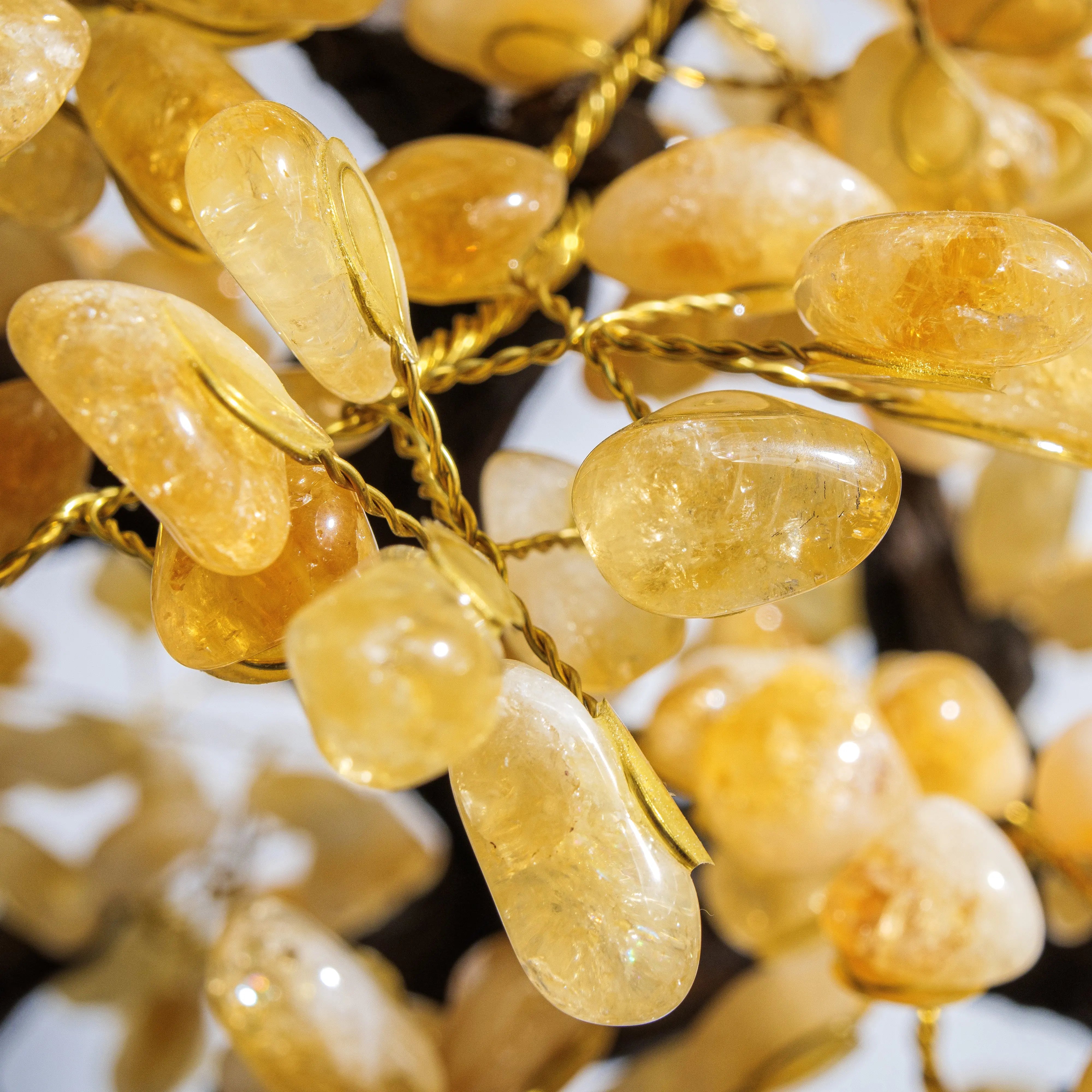 Close-up of handcrafted citrine crystal bonsai tree radiating positivity and abundance, featuring polished golden gemstones.