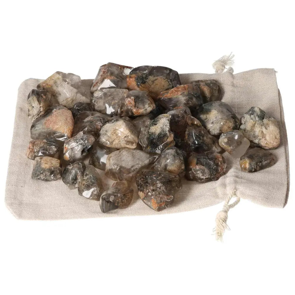 Tumbled Lodolite gemstones on a beige cloth, premium crystals by Sylvia Crystals for spiritual and mystical enhancement.