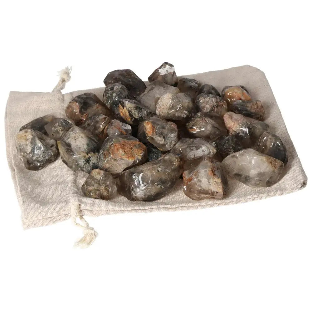A collection of Tumbled Lodolite gemstones from Sylvia Crystals on a drawstring pouch, showcasing elegance and mysticism.
