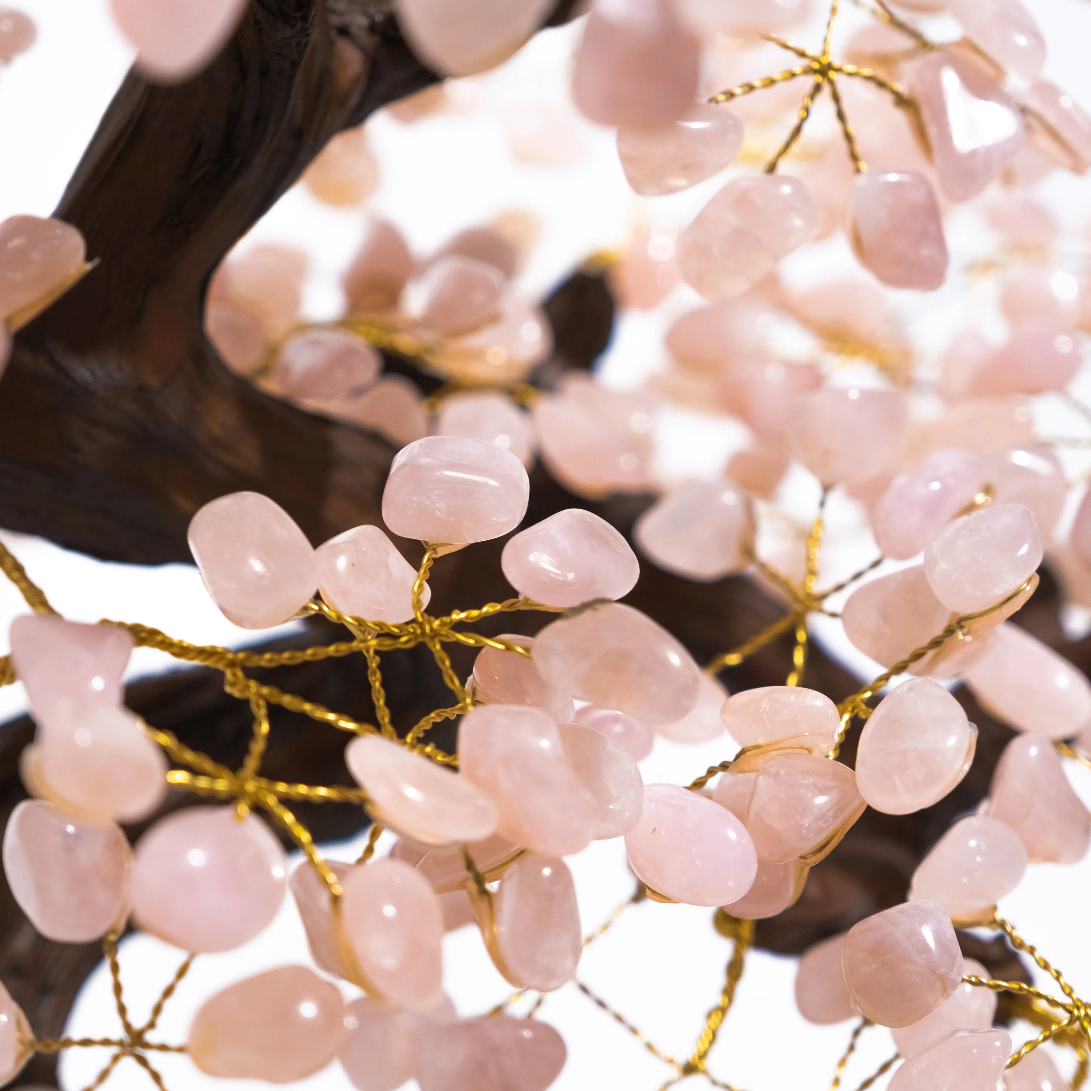 Close-up of pink quartz gemstones on a wire bonsai tree, showcasing natural beauty and positive energy in home décor.