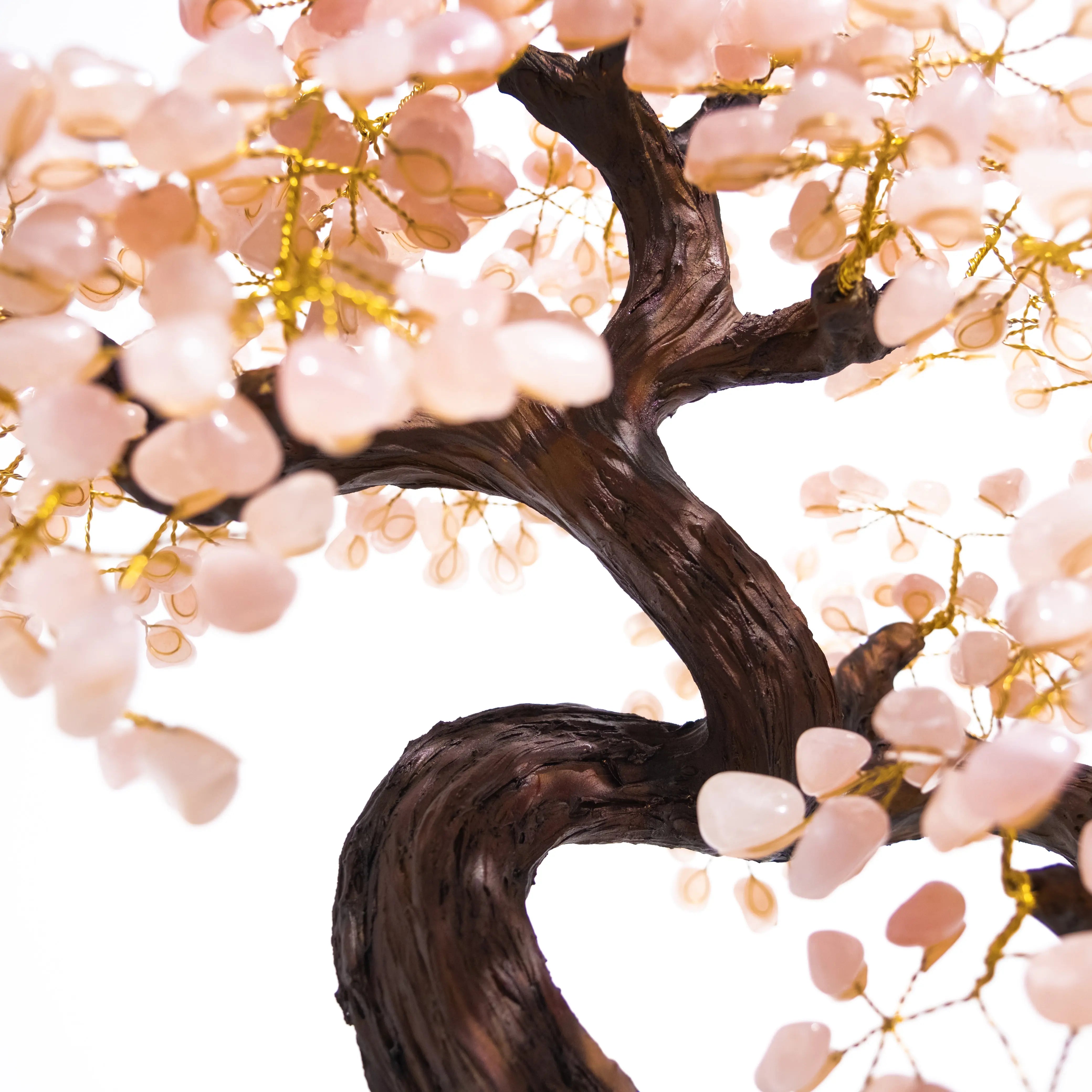 Close-up of a tumbled quartz crystal bonsai tree with pink gemstones on gold wire, showcasing intricate handcrafted details.
