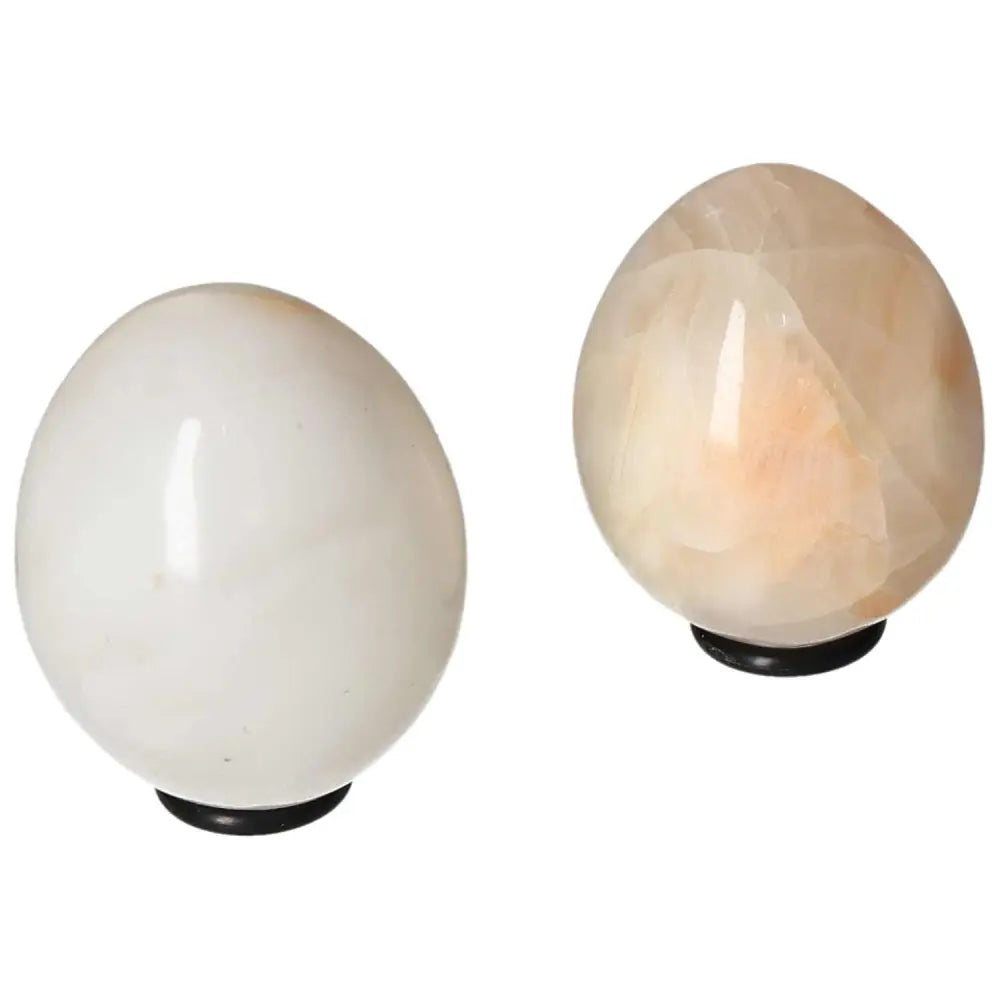 Pair of polished white onyx eggs on stands, known for promoting self-discipline and determination.