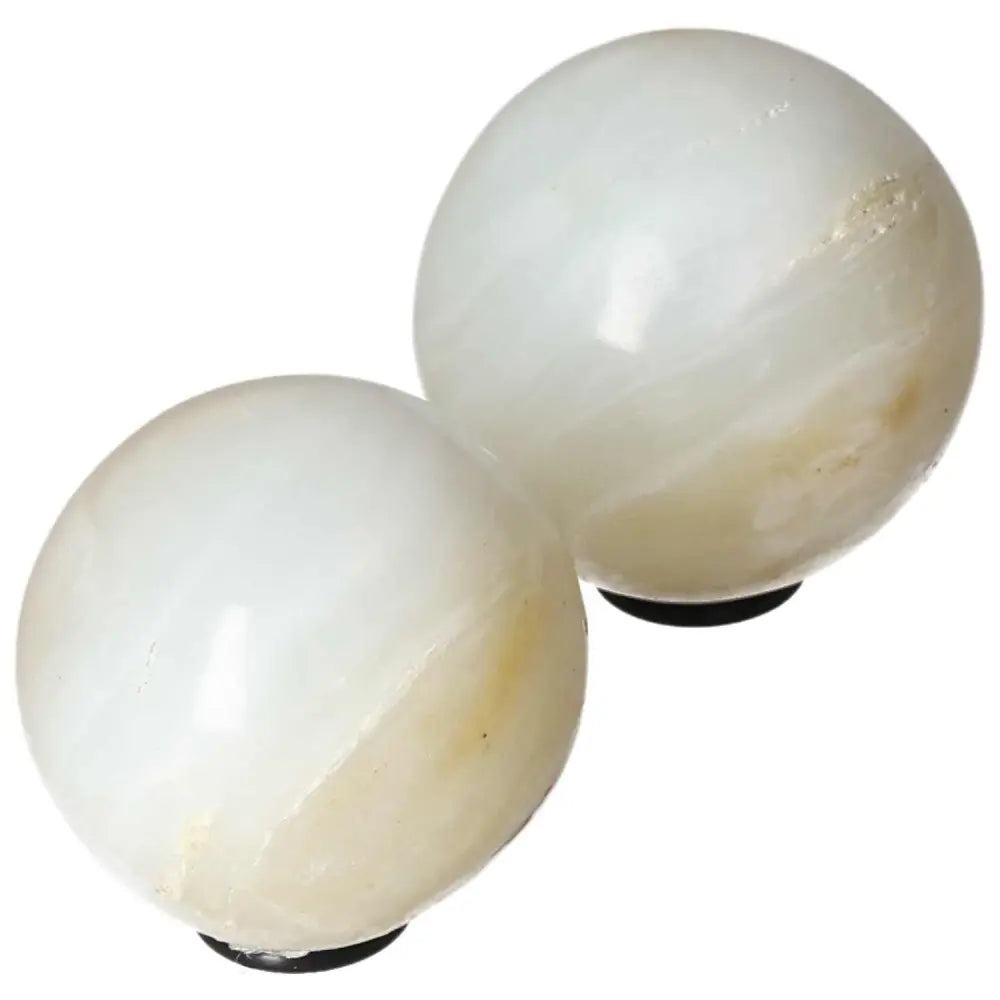 Two polished white onyx spheres on display, known for enhancing strength, determination, and self-discipline.