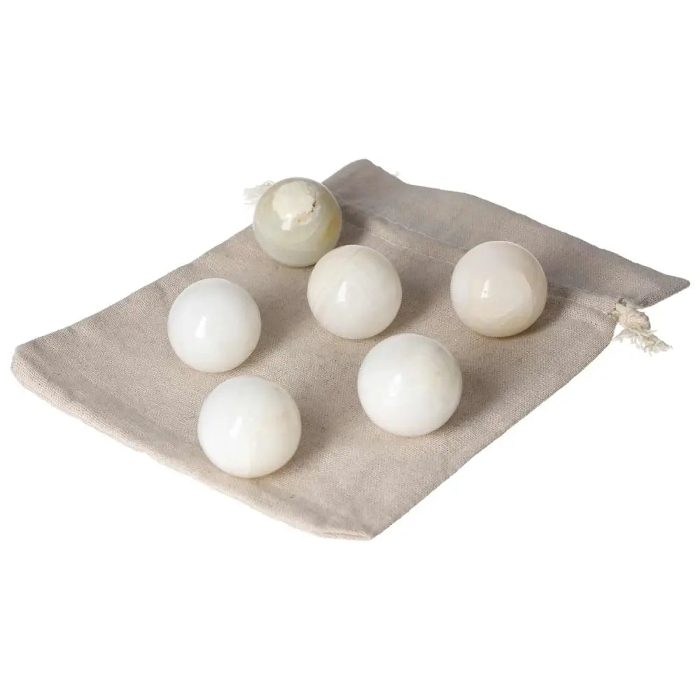 Set of white onyx spheres on a cloth bag, symbolizing strength and determination. Ideal for overcoming challenges.