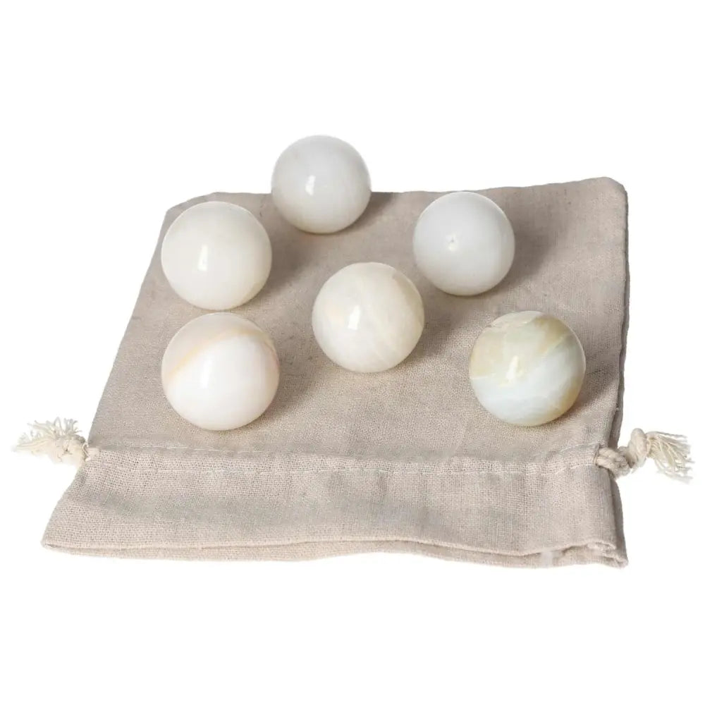 Six polished white onyx spheres on a beige cloth, symbolizing strength, determination, and self-discipline.