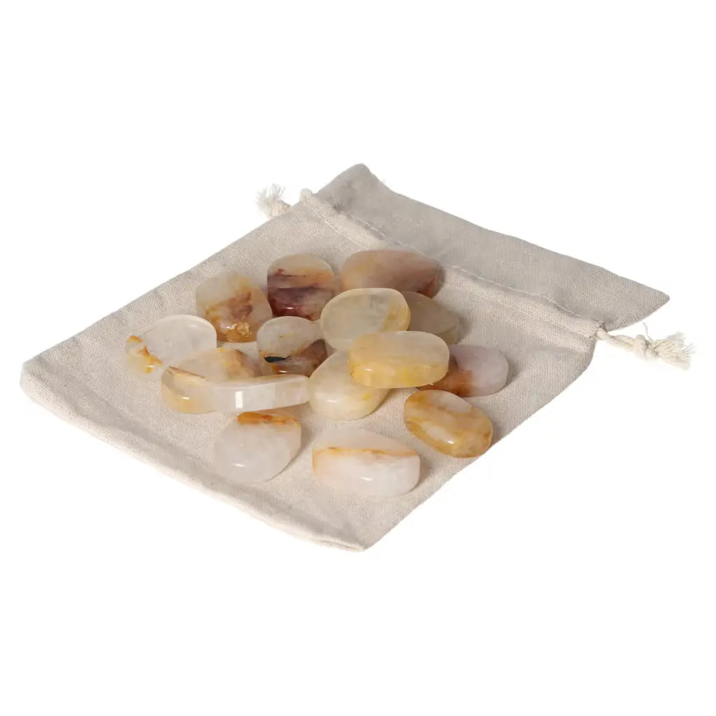 Yellow Hematoide crystal thumb massagers on beige pouch, promoting stress relief and tranquility from Sylvia Crystals collection.