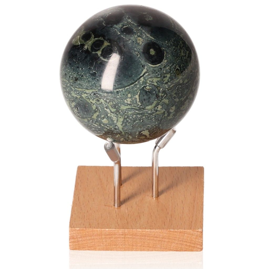 Kambaba Jasper Sphere on wooden stand, showcasing green and black patterns, known for promoting peace and grounding energy.