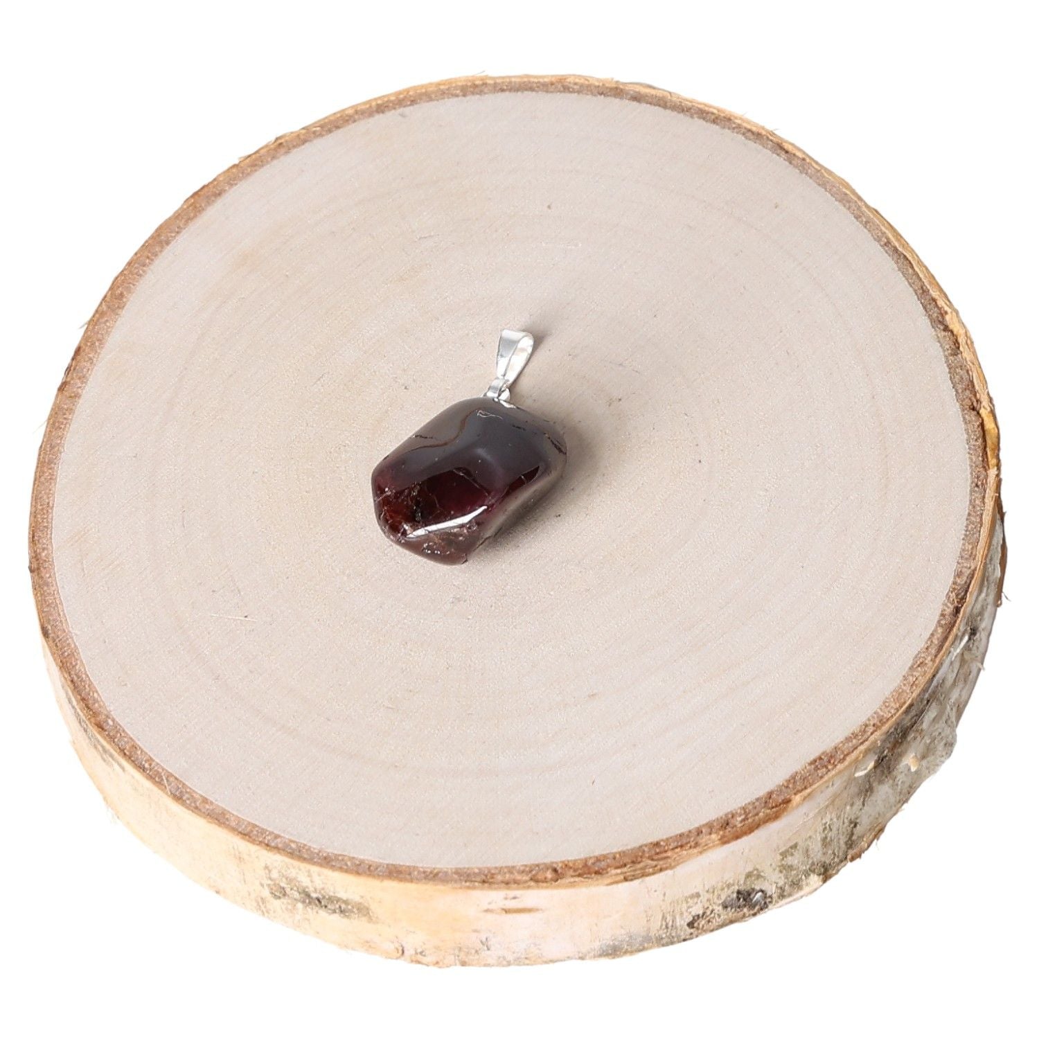 Garnet AA tumbled pendant on wooden slab, showcasing polished gemstone jewelry.