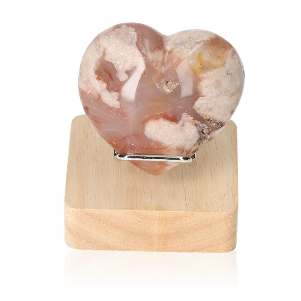 Heart-shaped Flower Agate gemstone on wooden stand, symbolizing tranquility and harmony.