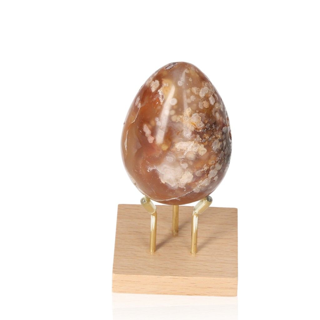 Flower Agate Egg on wooden stand, known for harmonizing energy and providing balance, security, and grounding.