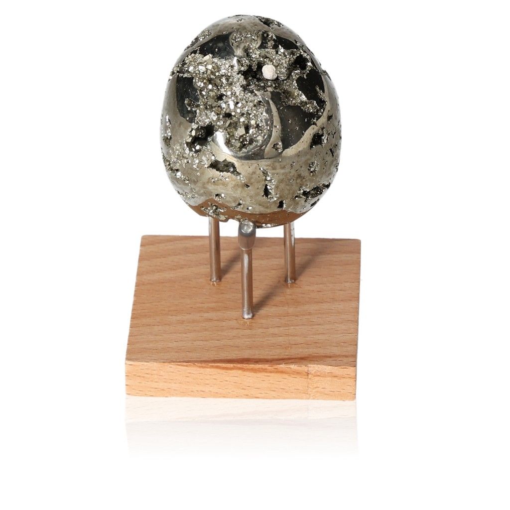 Sparkling pyrite egg on a wooden stand, symbolizing independence, creativity, and courage for personal growth and achievement.