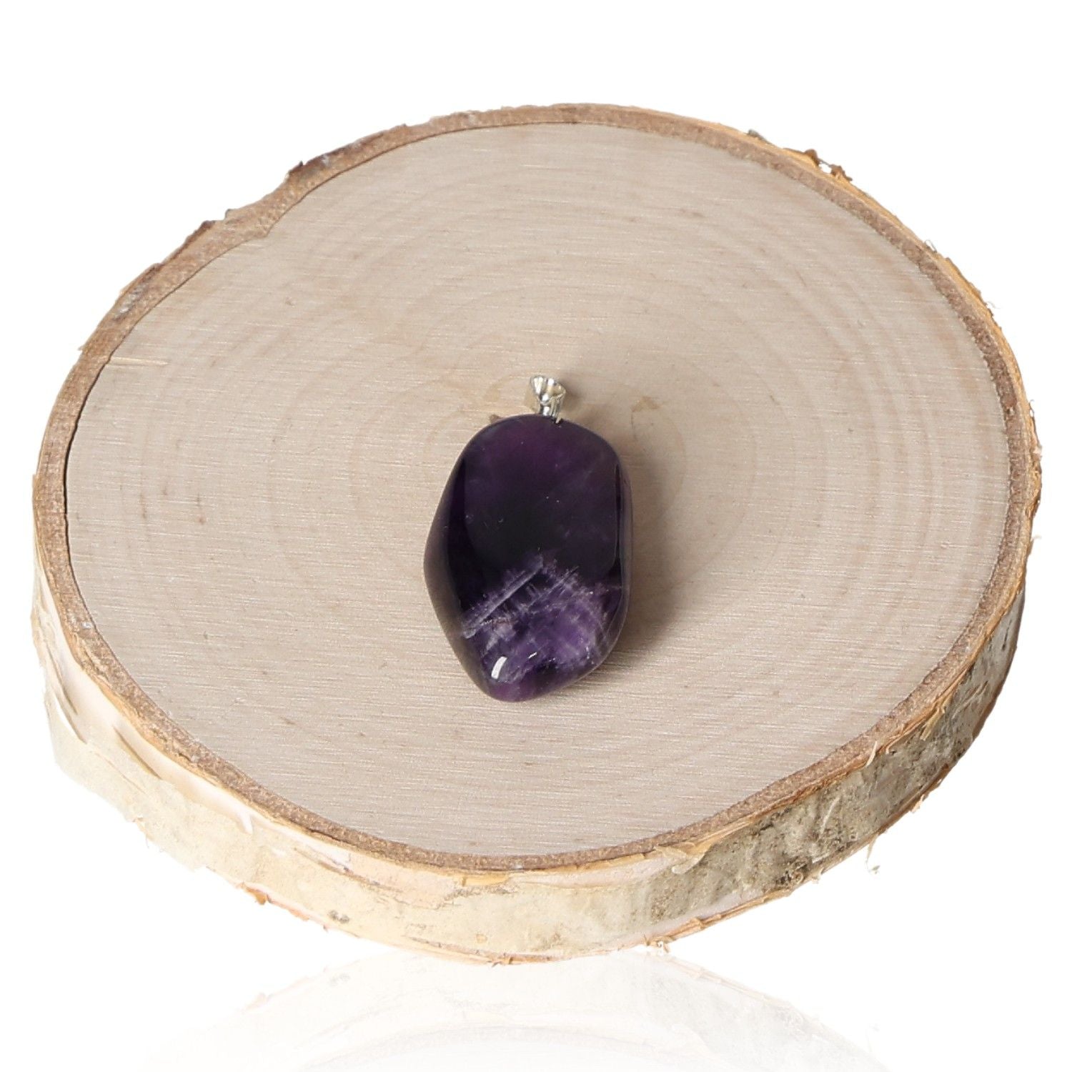 Amethyst Zambia tumbled pendant on wooden slab background, featuring deep purple hues and smooth polished surface.