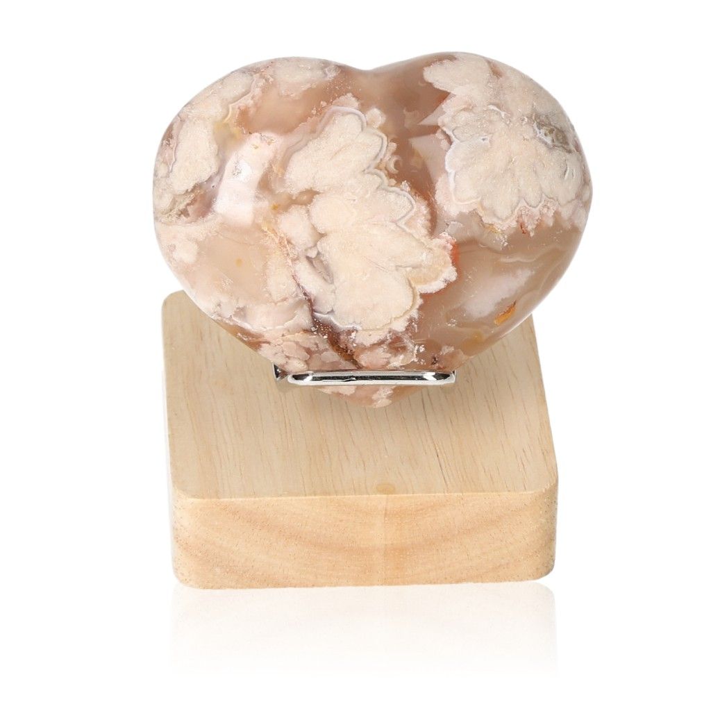 Flower Agate Heart gemstone on wooden stand, symbolizing tranquility and harmony.