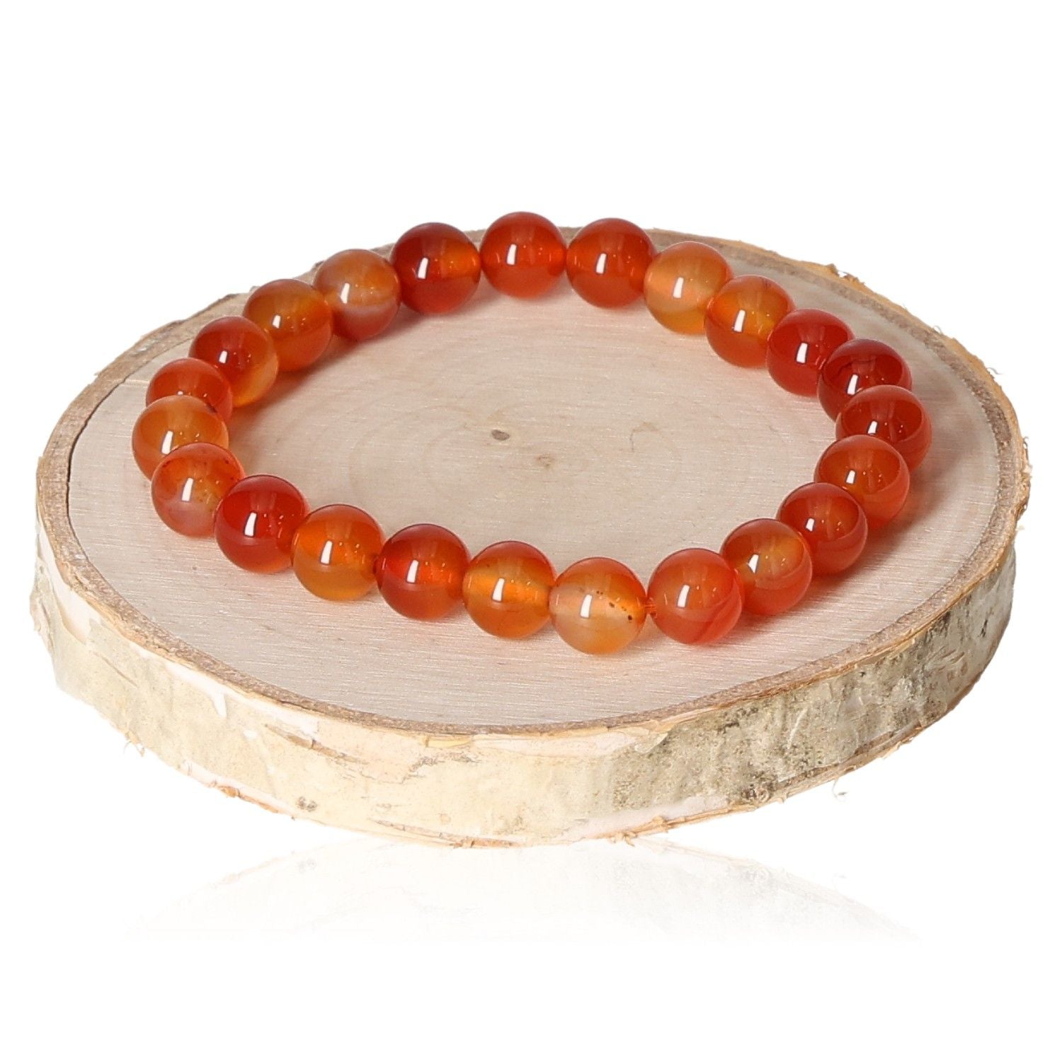 Carnelian bracelet 8mm with round orange beads displayed on a wooden disc for jewelry photography.